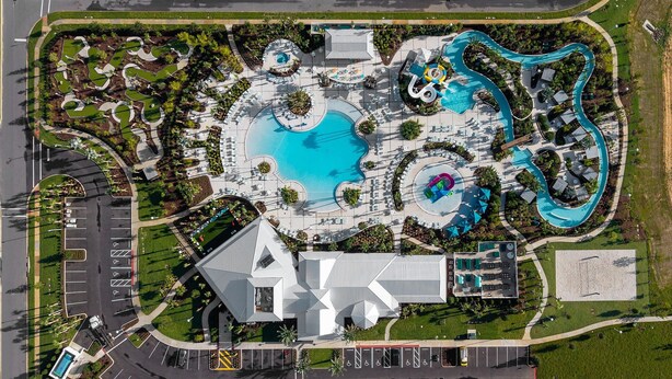 Vista aérea de un resort con una gran piscina central, varias piscinas más pequeñas y un tobogán de agua sinuoso.
