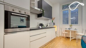 Et moderne køkken med indbygget ovn, mikroovn samt spiseplads med bord og stole.