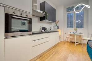 A modern kitchen with a built-in oven, a microwave, and a dining area with a table and chairs.