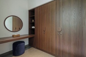 A room with a wooden wardrobe, a round mirror, a wooden bench, and a trash bin. - Villa Jenggala by GORO (Kabupaten Gianyar)