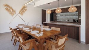 Un comedor moderno con una mesa de madera dispuesta para seis personas, rodeada de sillas de mimbre.