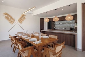 A modern dining area with a wooden table set for six, surrounded by wicker chairs. - Villa Jenggala by GORO (Kabupaten Gianyar)