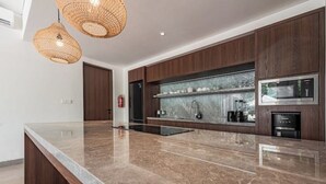 Una cocina moderna con encimera de mármol, armarios de madera y electrodomésticos integrados.