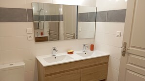 A bathroom with a white toilet, a wooden vanity with a sink, and a mirror above the vanity.