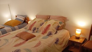 A neatly made bed with a feathered duvet, a bedside lamp, and a wooden nightstand.