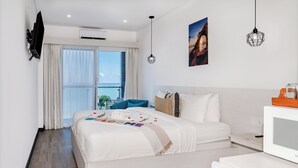 Camera d'albergo moderna con un letto grande, una televisione, una scrivania con un computer e vista mare dalla finestra.