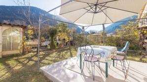 An outdoor patio with a table and chairs, surrounded by a tent and a mountain backdrop. - Apartment 'À Ria-sirach' with Mountain View, Shared Terrace and Wi-Fi (Ria-Sirach)