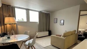 Una sala de estar moderna con una mesa de comedor redonda, dos sillas, un sofá y una lámpara.