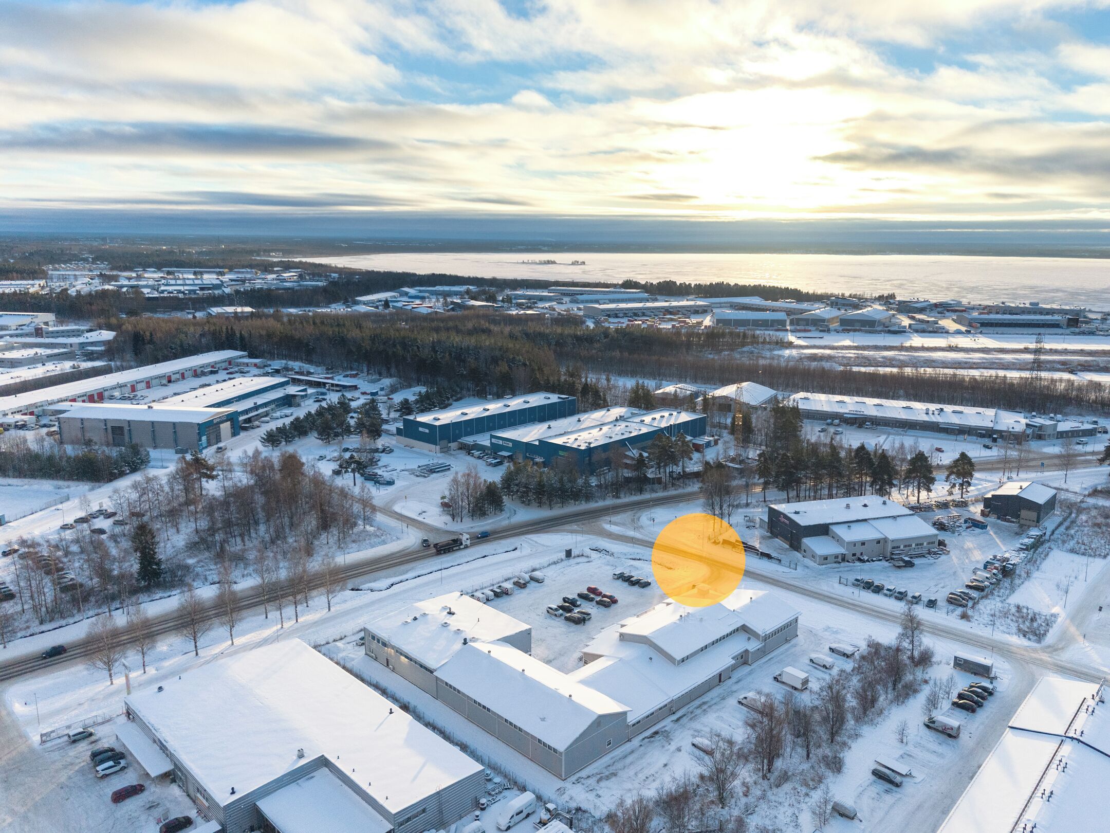 Vista aérea de una zona industrial cubierta de nieve, con varios edificios y estacionamientos.
