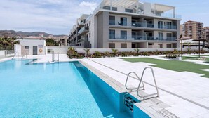 En moderne lejlighedskompleks med swimmingpool, altaner og anlagt have.