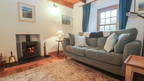 Una sala de estar acogedora con chimenea, un sofá, una alfombra y una ventana con cortinas.