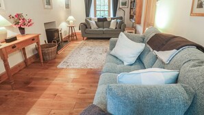 Una sala de estar acogedora con piso de madera, un sofá, una mesa con lámpara y una chimenea.