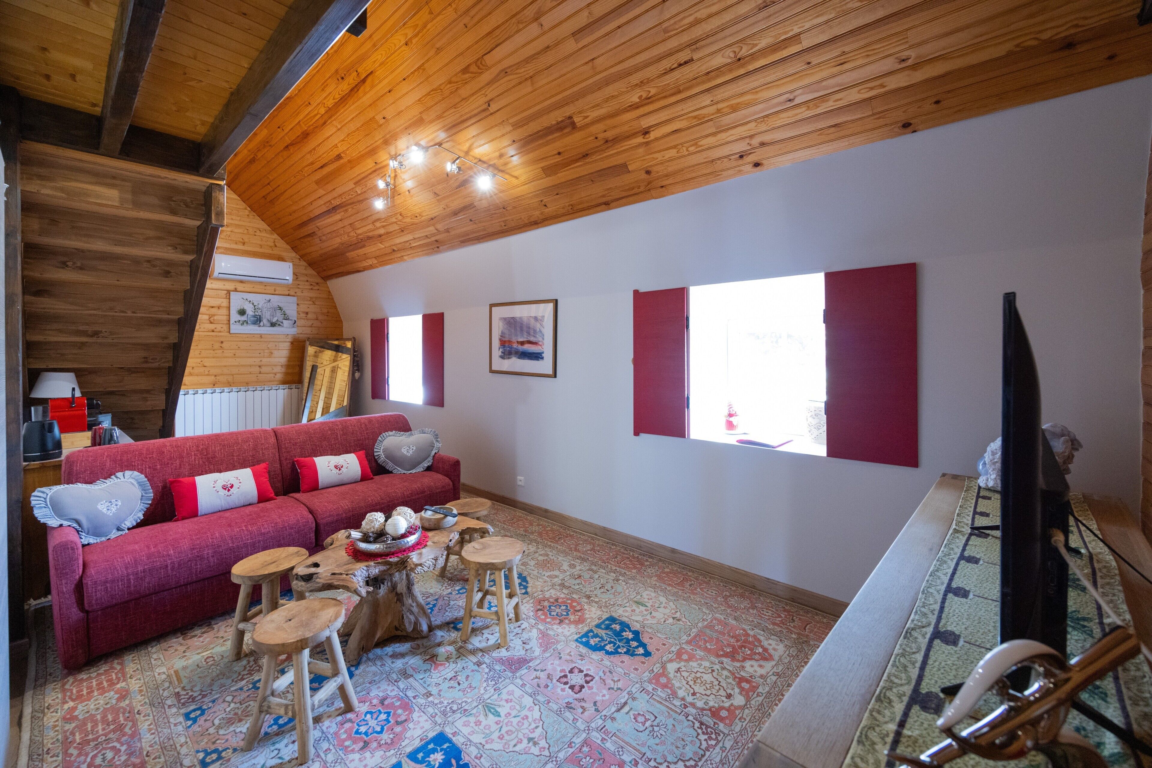 Ein gemütliches Wohnzimmer mit einem roten Sofa, einem Holztisch und einem gemusterten Teppich.