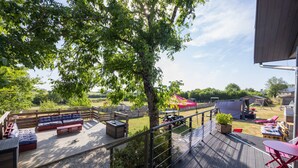 A deck with outdoor furniture, a covered seating area, and a view of a fenced yard.