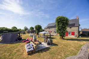A backyard with a barbecue setup, a tent, and a stone building with a red door. - “Chambre Raphaël” Guest Room with Mountain View, Wi-Fi, and Air Conditioning (Singles)