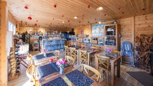 A wooden interior with tables, chairs, a kitchen, and a dining area. - “Chambre Raphaël” Guest Room with Mountain View, Wi-Fi, and Air Conditioning (Singles)