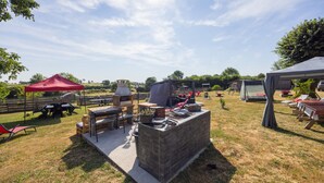 An outdoor patio with a barbecue grill, seating area, and a red tent. - “Chambre Raphaël” Guest Room with Mountain View, Wi-Fi, and Air Conditioning (Singles)