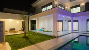 A modern two-story house with a swimming pool, a well-maintained lawn, and a patio area. - Teranga Blue (Ngaparou)