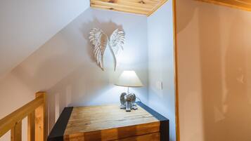 Een trap met houten leuning, een wandlamp en een decoratief engelbeeldje op een houten kist.