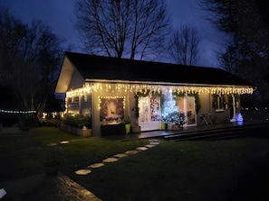 Una casa con porche decorado con luces y un árbol de Navidad.