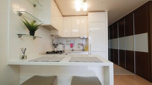 Una cocina moderna con armarios blancos, una isla central y un panel de pared de madera oscura.