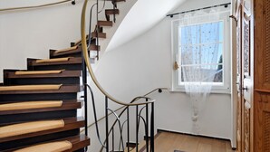 A spiral staircase with wooden steps and metal railings, leading to a room with a window and a door. - Holiday Home Feldberg in the Black Forest with Mountain Views, Terrace and Wi-Fi (Feldberg-Falkau)