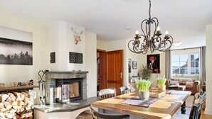 A spacious living room with a fireplace, a dining area with a large wooden table, and a chandelier. - Holiday Home Feldberg in the Black Forest with Mountain Views, Terrace and Wi-Fi (Feldberg-Falkau)