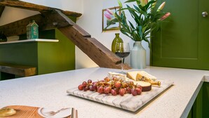 Eine Marmorarbeitsplatte mit einer Käse- und Weintraubentafel, einer Weinflasche und einer Blumenvase.