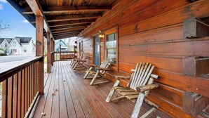Une terrasse en bois avec des chaises Adirondack et un espace couvert doté de poutres en bois.