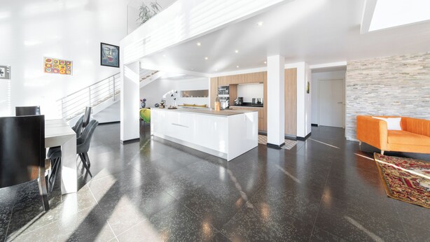 A modern open-plan living area with a kitchen, dining space, and a staircase.