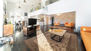 A spacious living area with a modern design, featuring a flat-screen TV, a coffee table, and a sofa.