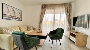 A modern living room with a sofa, two chairs, a coffee table, and a TV mounted on the wall. - Premium 4 stars Apartment Krk, 5 min to Beach & City Center, Smart TV, Netflix (Krk)