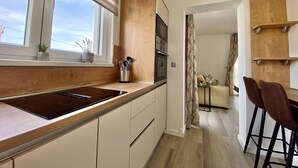 A modern kitchen with a large window, wooden cabinetry, and a built-in oven. - Premium 4 stars Apartment Krk, 5 min to Beach & City Center, Smart TV, Netflix (Krk)
