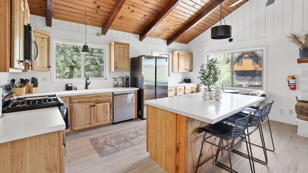 Une cuisine moderne avec des meubles en bois, un réfrigérateur en acier inoxydable et un grand îlot central doté de tabourets de bar.