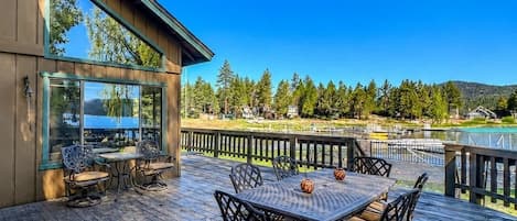 Une terrasse en bois avec une table et des chaises, donnant sur une étendue d’eau et une zone boisée.