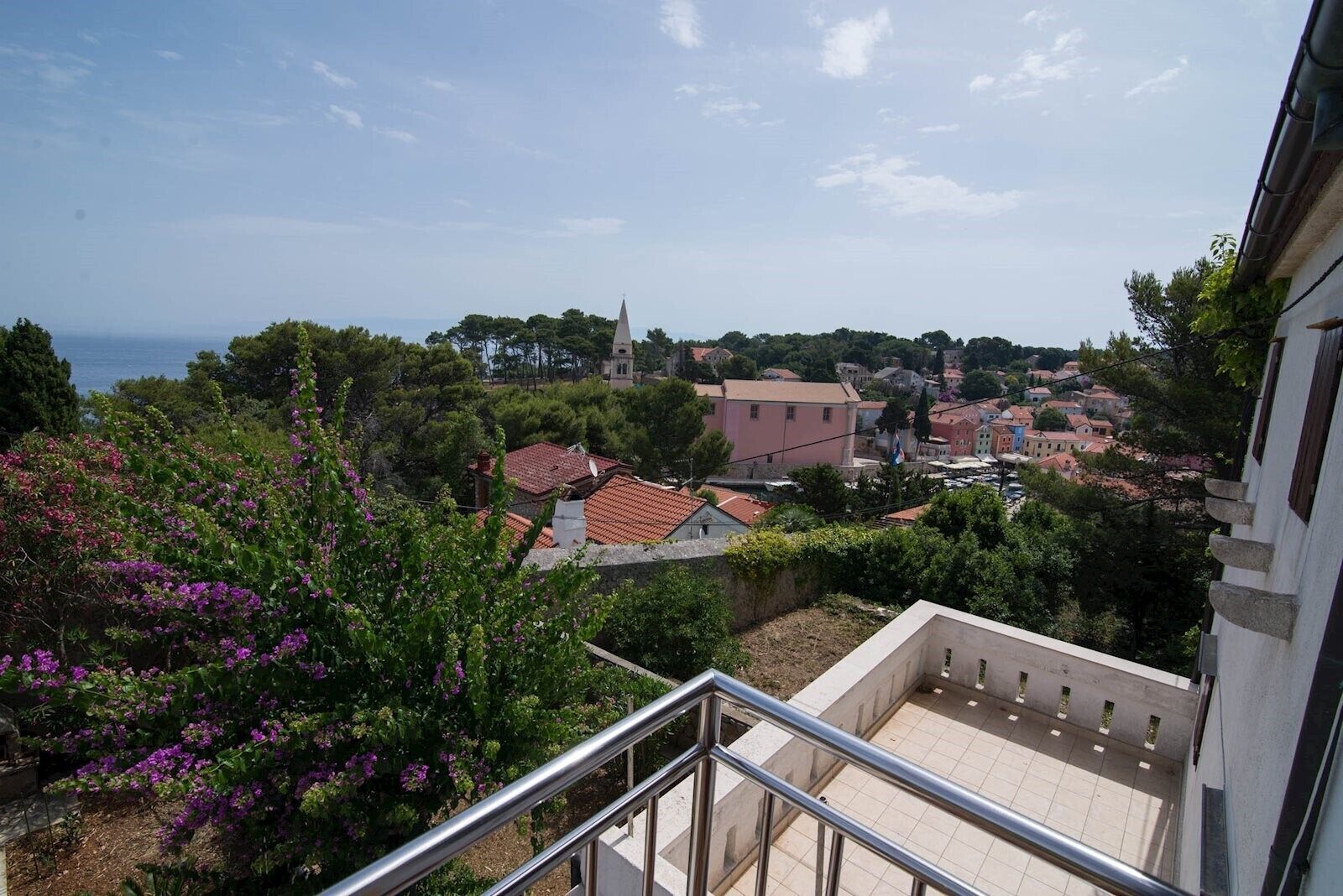 A residential area with a view of the sea, a church, and houses with red-tiled roofs.