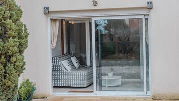 A modern house with a sliding glass door leading to a patio area with a patterned sofa and a small table.