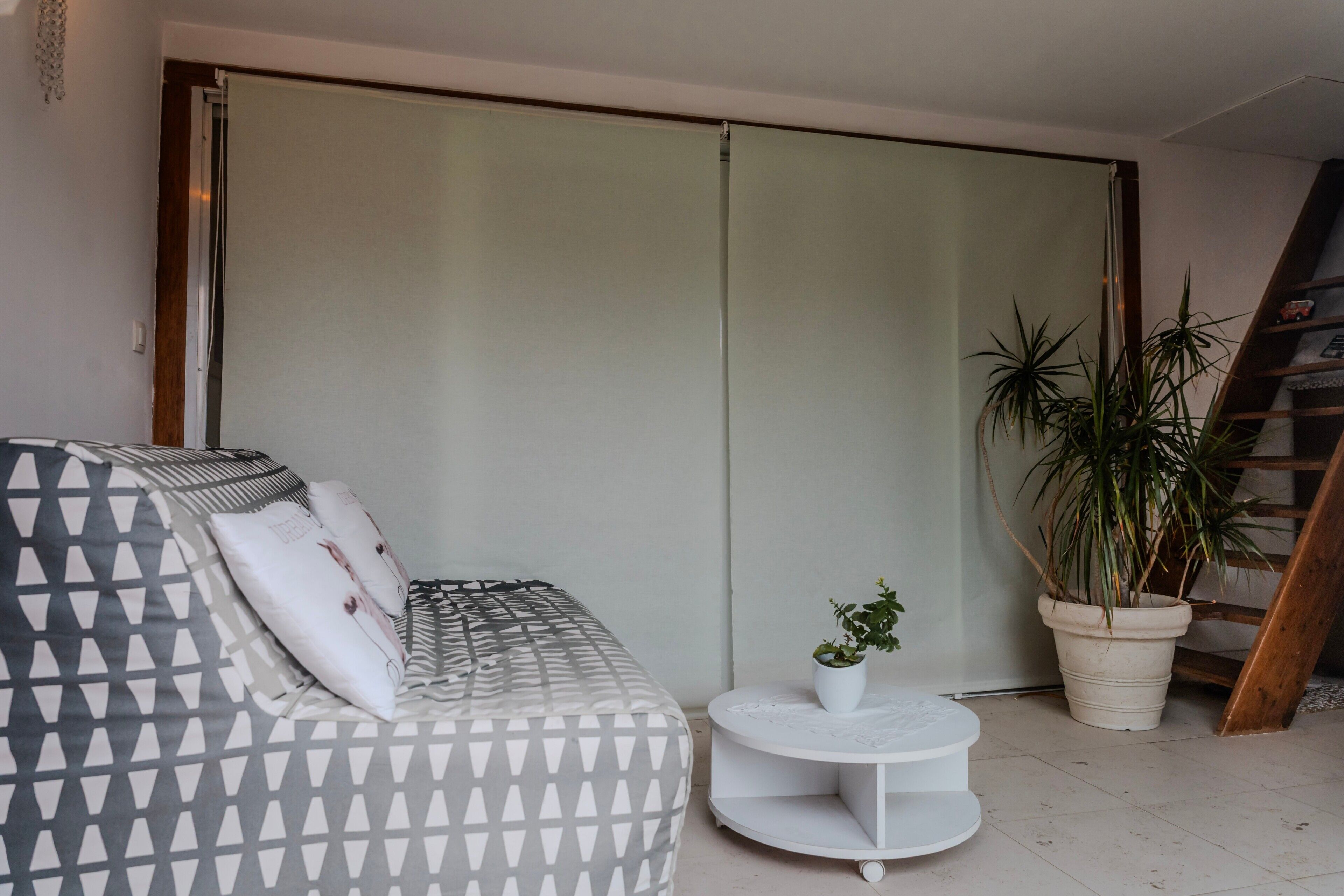 Een moderne woonkamer met een bank, een kleine witte tafel, een potplant en een schuifdeur.