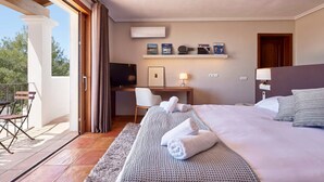 Een hotelkamer met een bed, bureau, stoel, televisie en balkon.