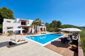 Una casa moderna con piscina, mobiliario exterior y un patio.