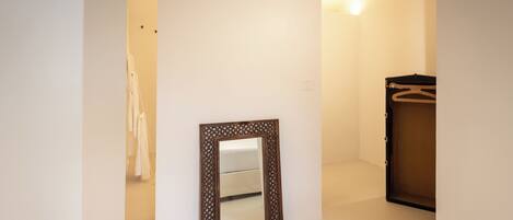 A room with a large mirror, a wardrobe, and a light fixture on the wall.
