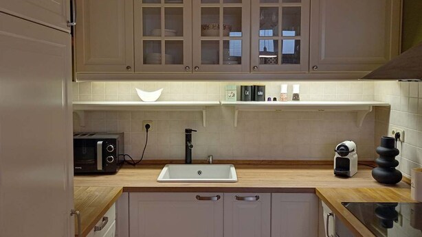 A kitchen with wooden cabinets, a white sink, a toaster, and a coffee maker. - Apartment with Cathedral View in Hradec Králové (Hradec Králové)
