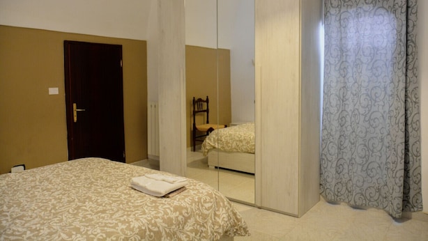 A bedroom with a bed, a wardrobe, and a mirror.