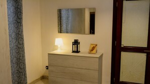 A wooden dresser with a mirror above it, a lamp, and a small decorative item on top.