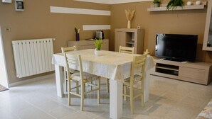 A dining area with a table and chairs, a radiator, a television, and a cabinet.