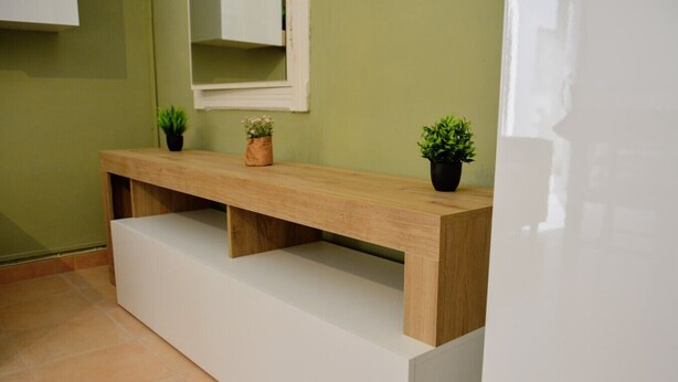 Un banc en bois doté de compartiments de rangement et agrémenté de deux plantes en pot.