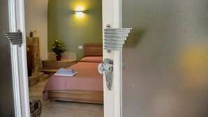 Une chambre à coucher avec un lit, une table de chevet, une lampe et une plante en pot.