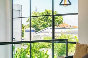 A room with large windows offering a view of greenery and a building.