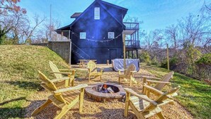 Une maison en bois à deux étages, dotée d’un foyer extérieur et d’un espace salon extérieur.