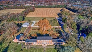 An aerial view of a large estate with a central building, expansive fields, and a variety of trees. - The Black Log Cabin - Hot Tub & Game Room (Fredericksburg)